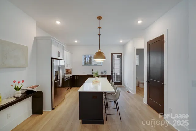 a large kitchen with a large counter top a refrigerator and cabinets