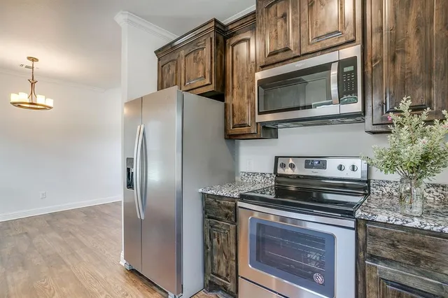 a kitchen with stainless steel appliances granite countertop a stove microwave and refrigerator