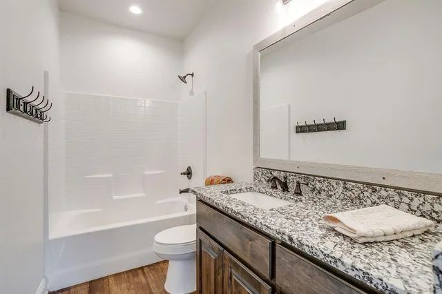 a bathroom with a granite countertop sink a toilet and bathtub