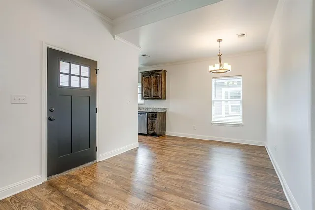 an empty room with wooden floor chandelier and windows