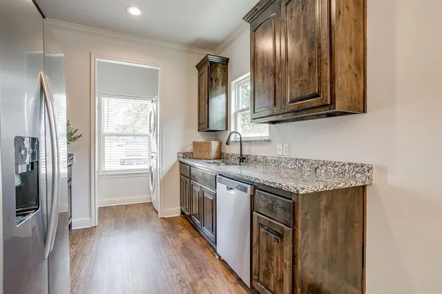 a kitchen with granite countertop stainless steel appliances a sink stove top oven and refrigerator