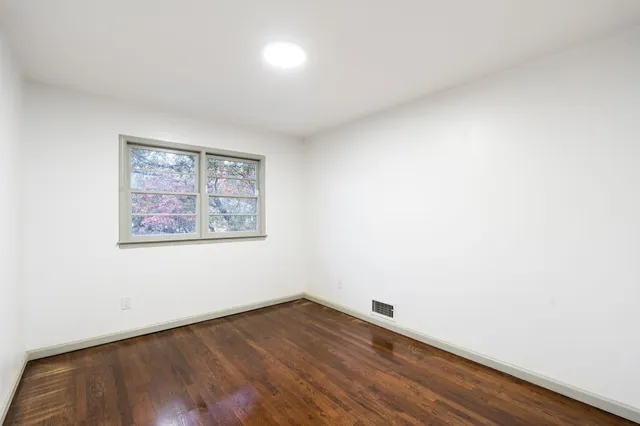 an empty room with wooden floor and window