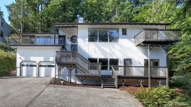 a view of a house with large wooden deck and furniture