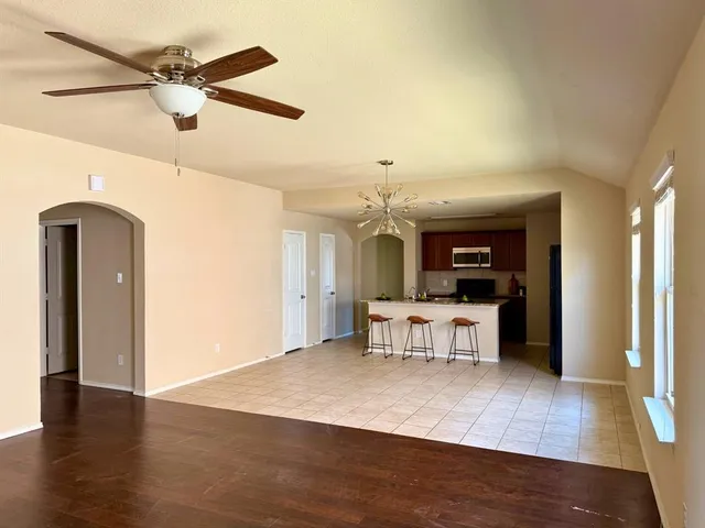 a view of a kitchen with a sink dishwasher a refrigerator with wooden floor and a dining table