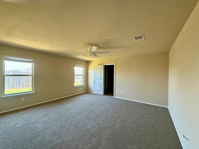 an empty room with windows and chandelier fan