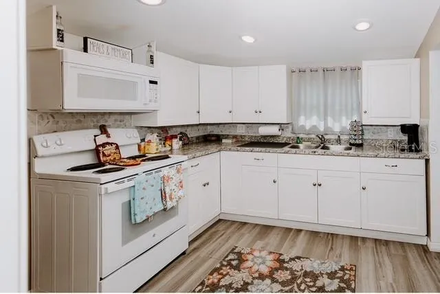 a kitchen with granite countertop white cabinets and white appliances