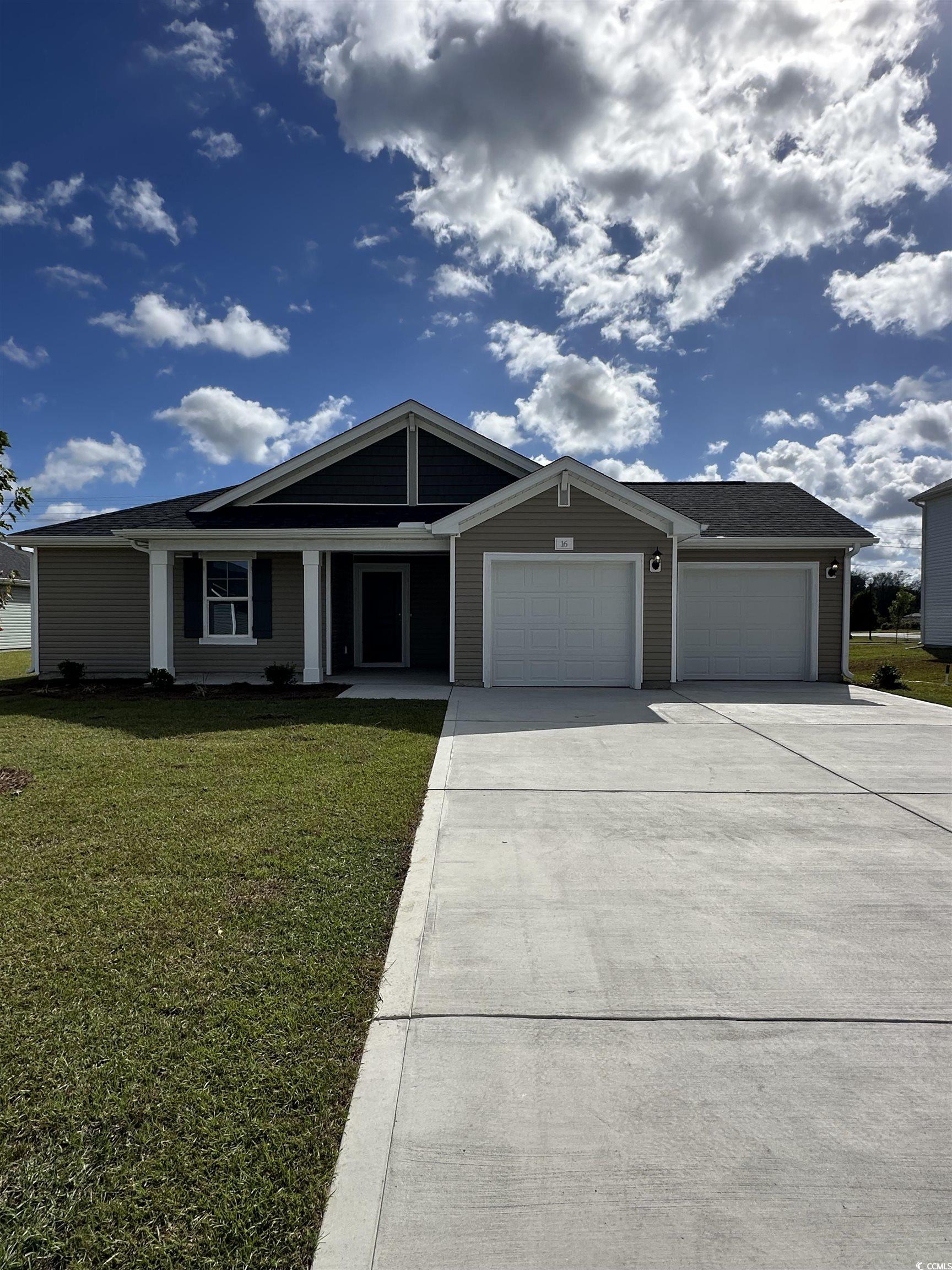 View of front of property with a front yard, driveway, an attached garage, and covered porch