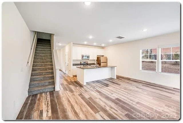 a view of kitchen with kitchen island wooden floor and living room