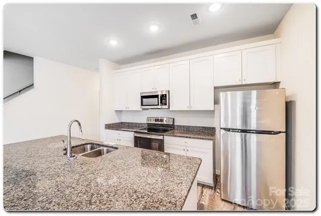 a kitchen with granite countertop a refrigerator stove and sink
