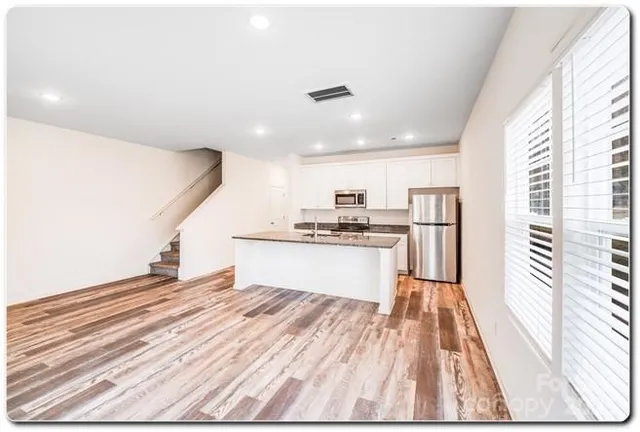 a kitchen with stainless steel appliances kitchen island granite countertop a refrigerator and a stove top oven