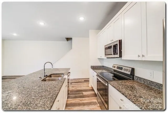 a kitchen with stainless steel appliances granite countertop a sink stove and cabinets