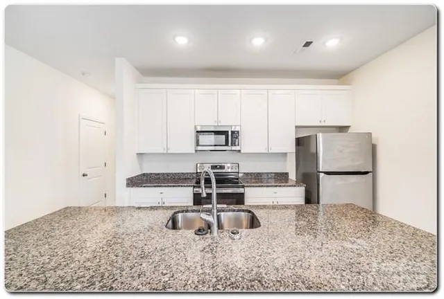 a kitchen with stainless steel appliances granite countertop a sink stove and refrigerator