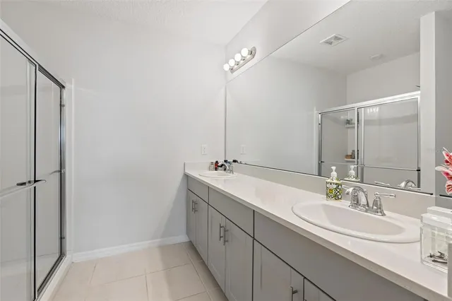a bathroom with a double vanity sink a mirror and a shower