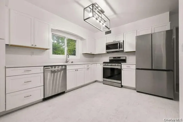 a kitchen with cabinets stainless steel appliances and window