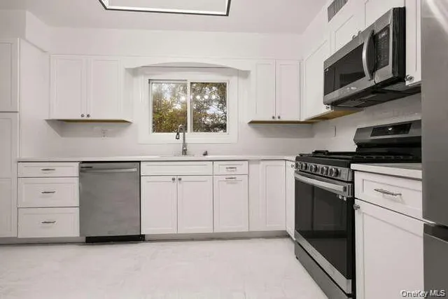 a kitchen with white cabinets and appliances