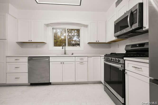 93 Seton Drive New Rochelle, NY 10804 - Photo 10 of 31 a kitchen with white cabinets and appliances
