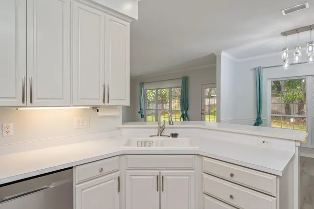 a kitchen with white cabinets and sink