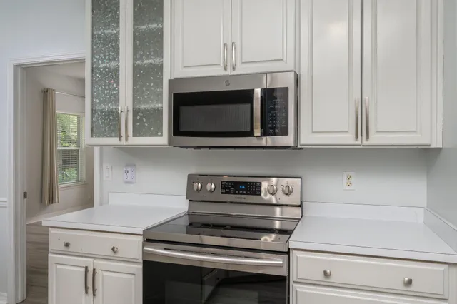 a kitchen with stainless steel appliances granite countertop white cabinets and a stove top oven