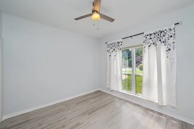 a view of an empty room with window and wooden floor