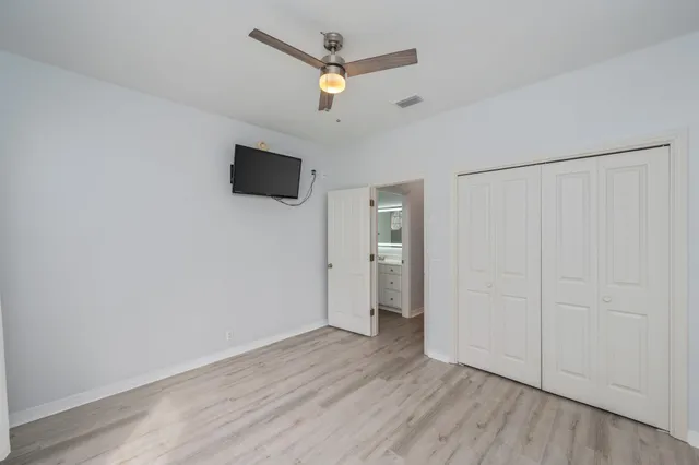an empty room with wooden floor and ceiling fan