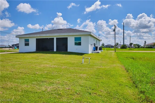 a view of a house with a yard and a large tree