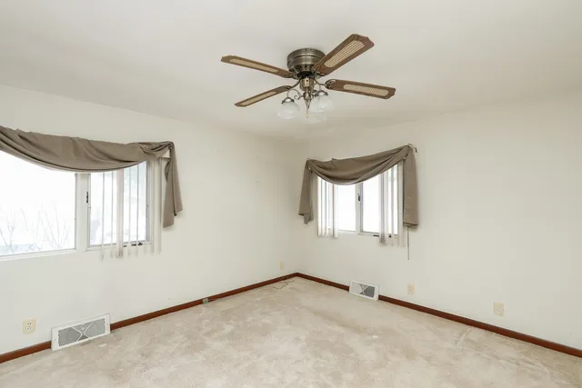 an empty room with windows and fan