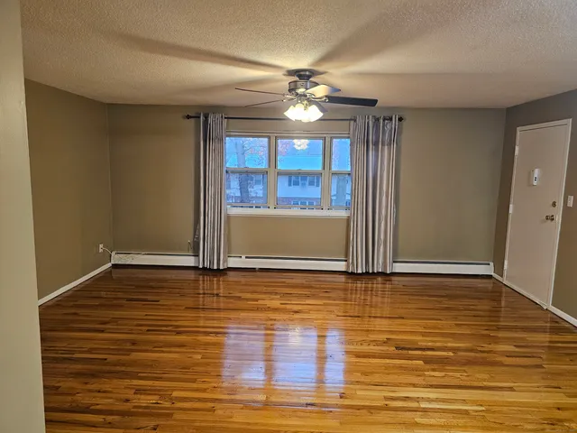 a view of an empty room with window and wooden floor