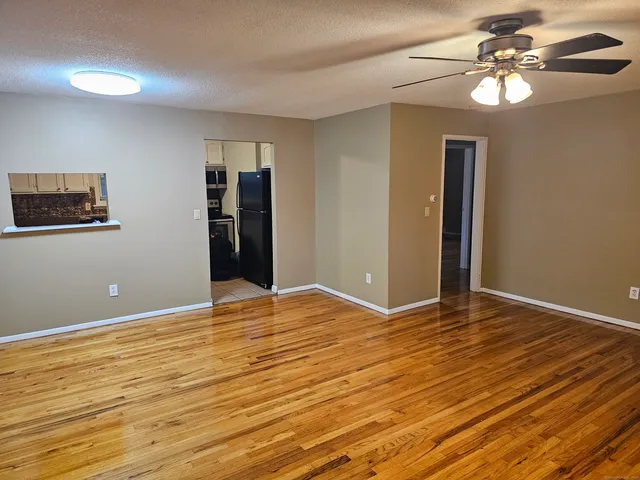 a view of an empty room with window and wooden floor