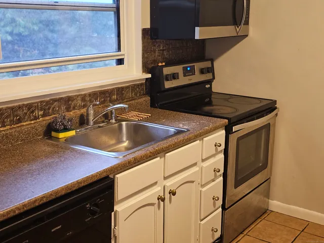 a close view of a sink a stove and kitchen counter top space