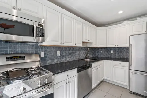 a kitchen with granite countertop a sink stove and white cabinets