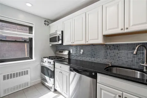 a kitchen with granite countertop a sink stove and cabinets