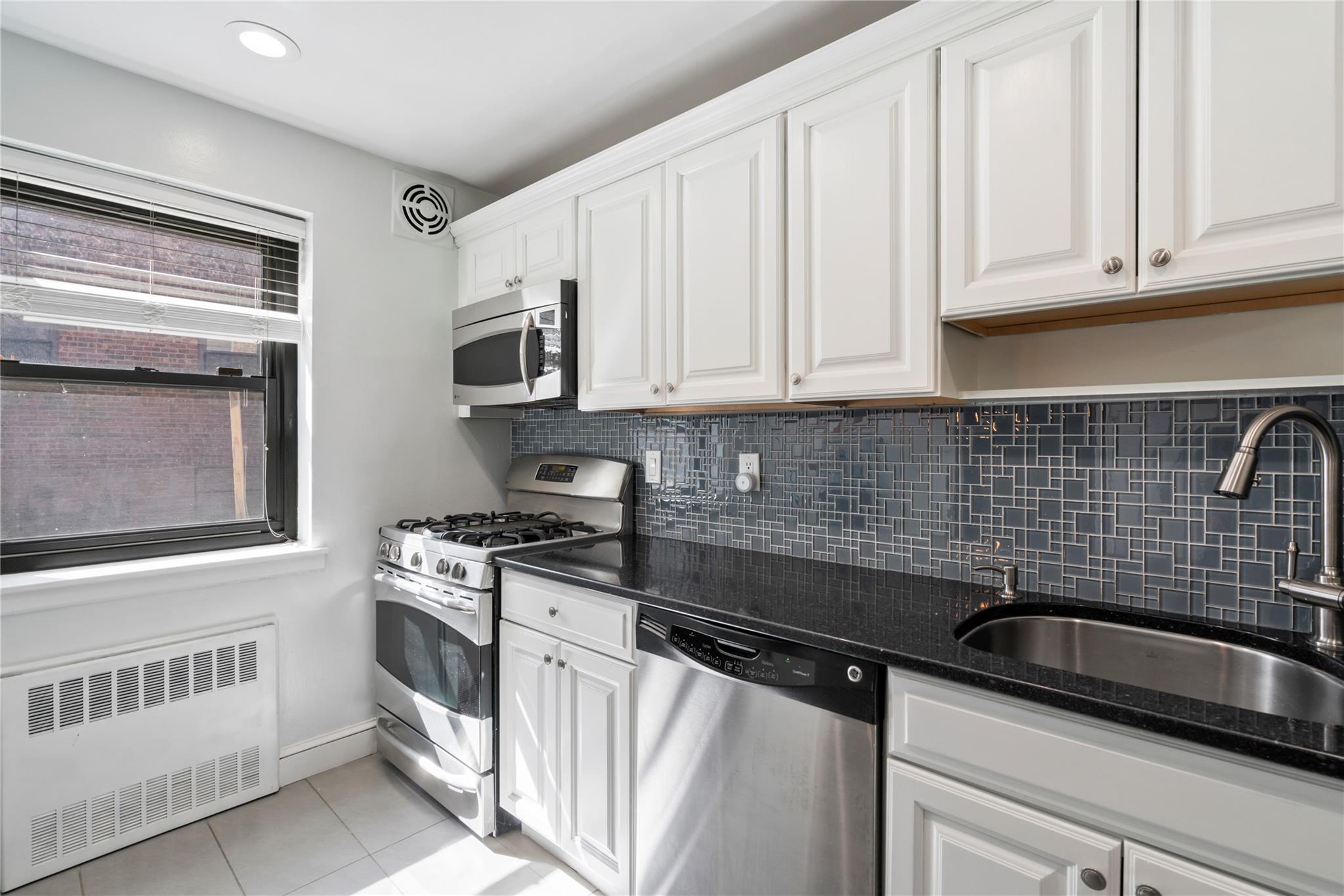 50 Brompton Road, Unit 1T Great Neck, NY 11021 - Photo 14 of 33 a kitchen with granite countertop a sink stove and cabinets