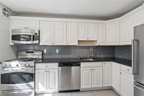a kitchen with white cabinets and appliances