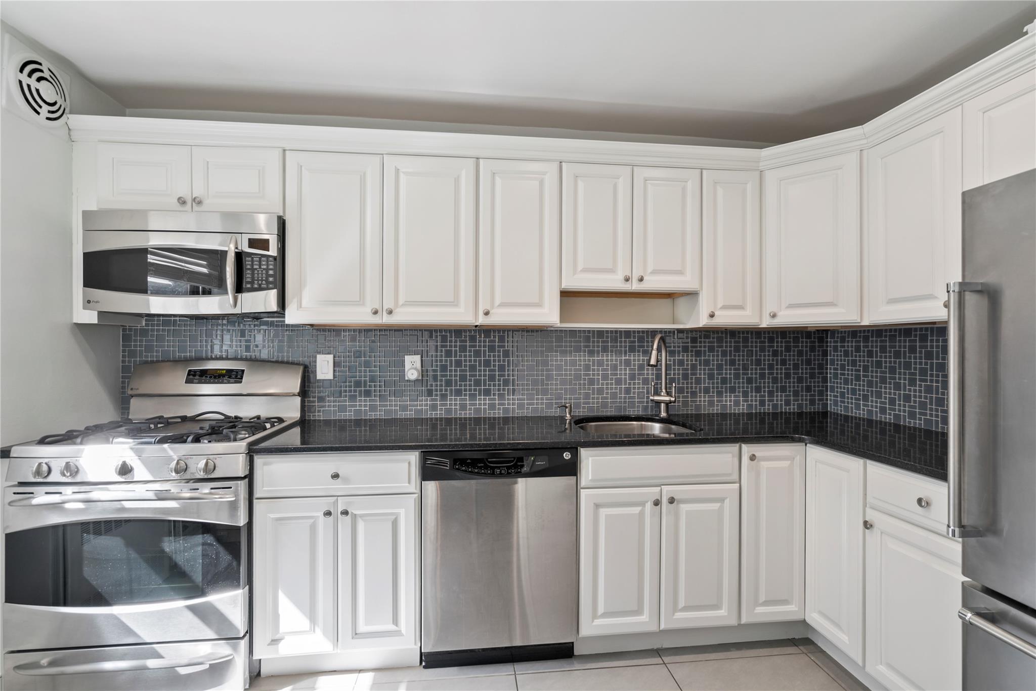 50 Brompton Road, Unit 1T Great Neck, NY 11021 - Photo 16 of 33 a kitchen with white cabinets and appliances