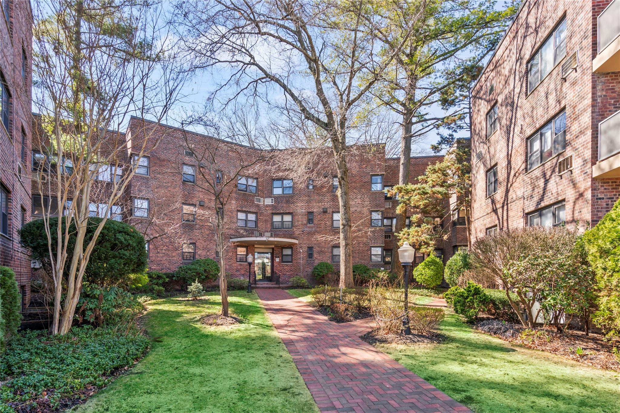 50 Brompton Road, Unit 1T Great Neck, NY 11021 - Photo 23 of 33 a view of a big building with a yard and large trees