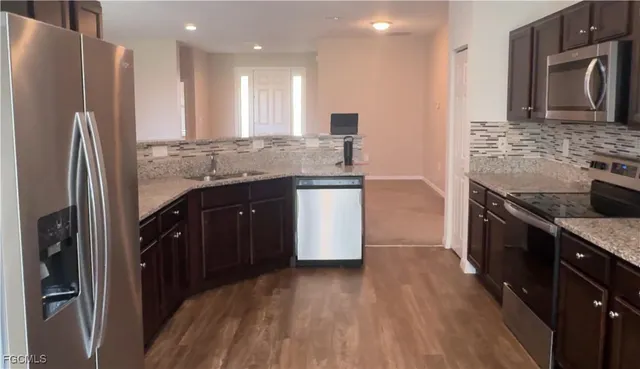 a kitchen with stainless steel appliances granite countertop a refrigerator a stove and a sink