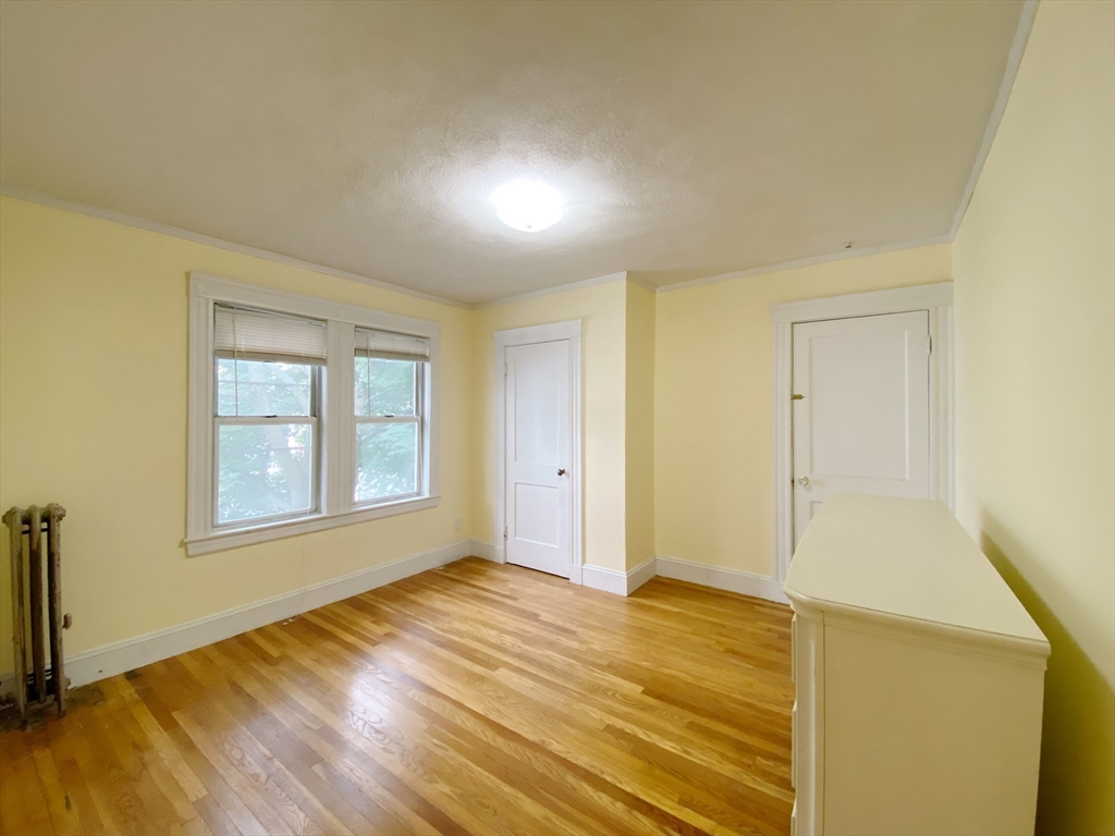 9 Cresthill Road, Unit 2 Somerville, MA 02145 - Photo 14 of 18 a view of an empty room with wooden floor and a window