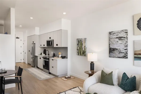 a kitchen with stainless steel appliances kitchen island granite countertop a refrigerator a stove a sink a dining table and chairs with wooden floor