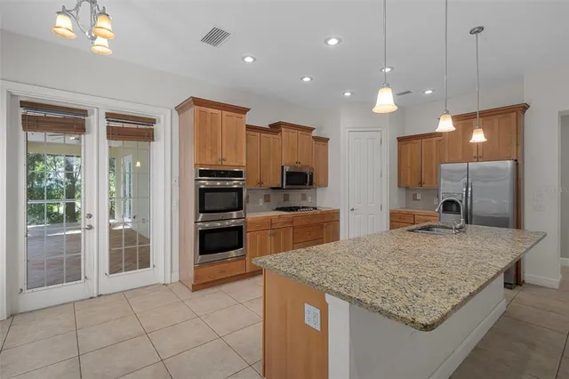 an empty room with a chandelier fan and windows