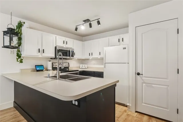 a kitchen with stainless steel appliances a sink a stove a refrigerator and white cabinets