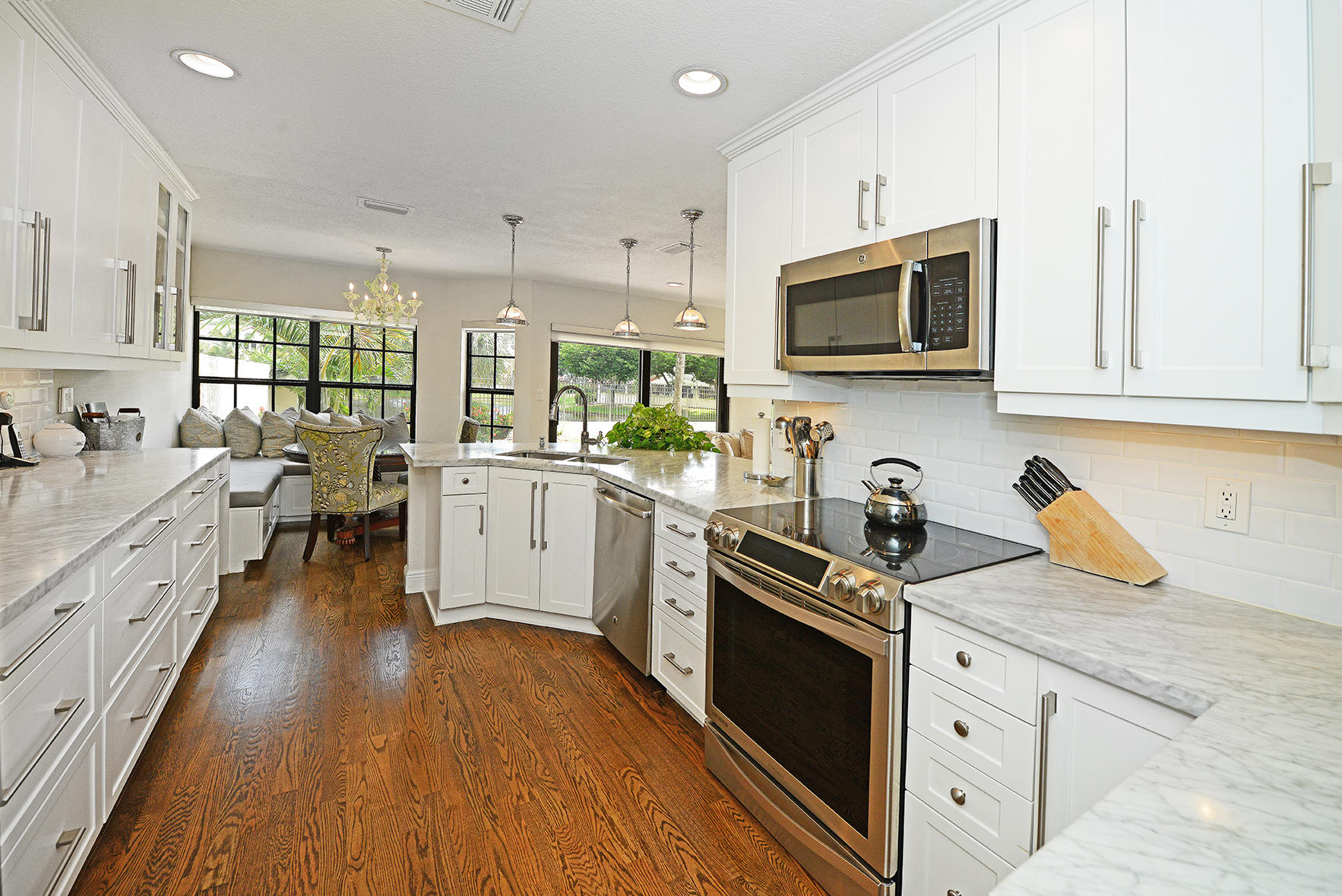 21760 Club Villa Terrace Boca Raton, FL 33433 - Photo 21 of 38 a kitchen with stainless steel appliances granite countertop a sink dishwasher stove and white cabinets with wooden floor