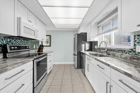 a large kitchen with stainless steel appliances granite countertop a stove and a sink