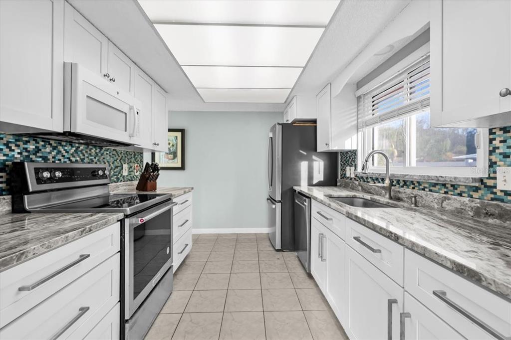 4880 Shell Stream Boulevard New Port Richey, FL 34652 - Photo 4 of 25 a kitchen with stainless steel appliances granite countertop a stove a sink and a refrigerator