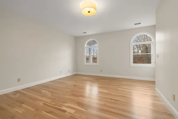 a view of empty room with wooden floor and window