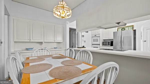 a kitchen with stainless steel appliances granite countertop a sink dishwasher a stove a dining table and chairs with wooden floor