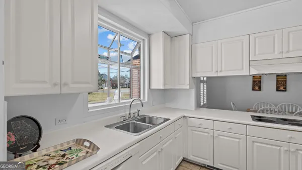 a kitchen with white cabinets and window