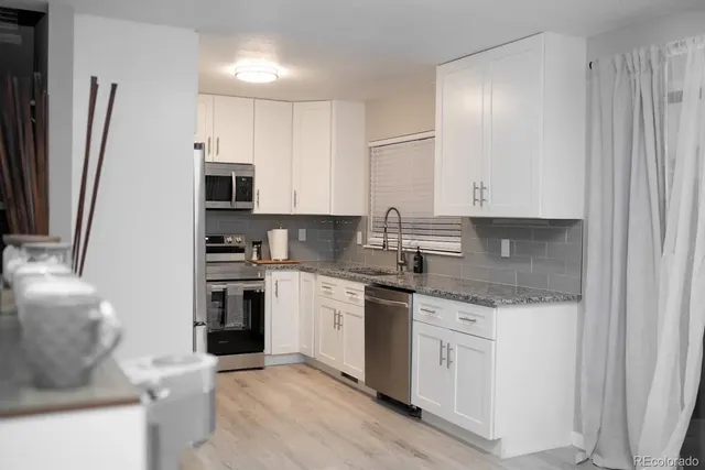 a kitchen with stainless steel appliances granite countertop a stove a sink and a refrigerator