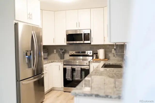 a kitchen with stainless steel appliances granite countertop a refrigerator a stove and a microwave