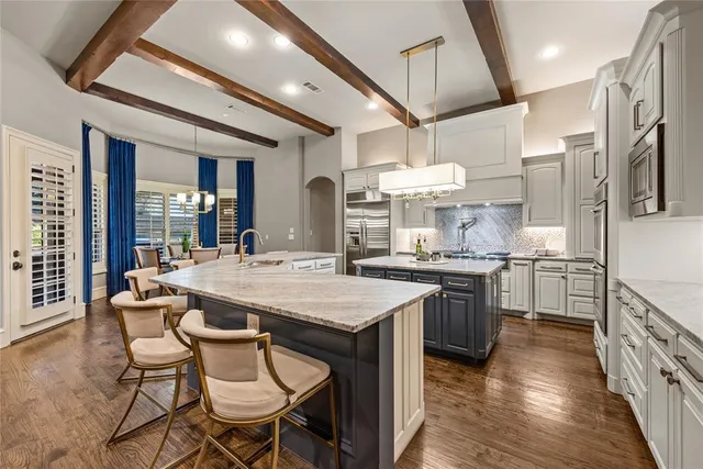 a kitchen with stainless steel appliances granite countertop a stove top oven a sink dishwasher a dining table and chairs with wooden floor