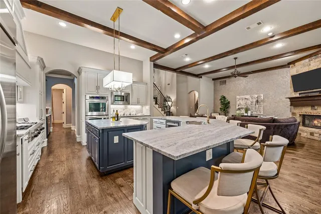 a dining hall with stainless steel appliances granite countertop a stove a sink dishwasher and chairs with wooden floor